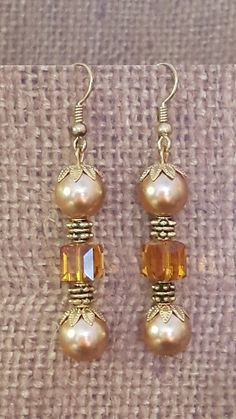 "Pretty earrings with goldtone pearls and Swarovski square bead, small goldtone elements & bead caps Pearls are 8mm each Square bead is 5mm Earrings are approximately 5.5cm (2 1/4\") long from top of hook Handmade original Each pair comes with rubber backings Thanks for visiting my shop!" Pearl Drop Earrings With Gold Beads, Gold Beaded Dangle Earrings With Pearl Drop, Gold Dangle Beaded Earrings With Pearl Drop, Gold Pearl Drop Beaded Earrings, Gold Beaded Drop Earrings For Formal Occasions, Gold Beaded Pearl Earrings, Handmade Gold Pearl Beaded Earrings, Pearl Earrings With Gold Beads For Gift, Gold Pearl Earrings With Gold Beads