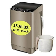 a small washing machine next to a cup on a white surface with a yellow label reading 15 6lbs