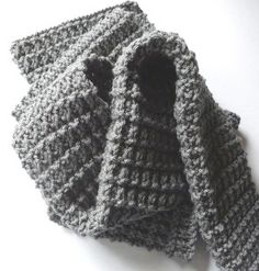 two knitted gray mittens sitting on top of a white table