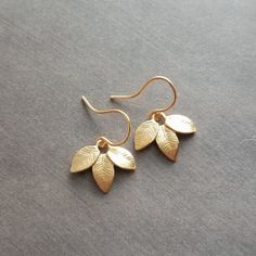 Little leaflet trios with a beautiful little engraved veining pattern on each leaf done in a matte gold plated finish over brass (not a super shiny high-polished finish). The simple ear hooks themselves are also gold-plated brass and *do* have a shiny polished finish.  These are elegant as well as being a perfect fit for an everyday outfit. **Last 5 photos shows these earrings in a silver finish- sold separately here: https://www.etsy.com/listing/167814546/silver-leaf-earrings-delicate-leaf-bunc Leaf-shaped Gold Jewelry For Wedding, Minimalist Gold Leaf Earrings, Gold Leaf-shaped Jewelry For Wedding, Handmade Gold Earrings For Bridesmaid Gift, Handmade Gold Earrings For Bridesmaids, Leaf-shaped Wedding Jewelry With Matching Earrings, Delicate Gold Leaf-shaped Jewelry, Handmade Leaf-shaped Earrings For Weddings, Handmade Leaf-shaped Wedding Earrings