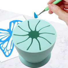 a hand holding a green plastic object with a butterfly on it