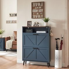 a blue cabinet in a living room next to a brown chair and potted plant