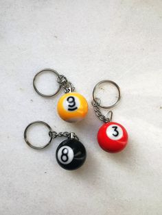 three pool ball keychains with numbers on them sitting next to each other in front of a white background