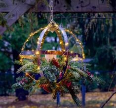 a christmas decoration hanging from a tree with lights on it's branches and surrounded by greenery