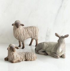 three ceramic sheep laying down next to each other