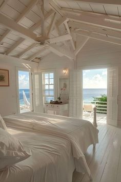 two beds in a room with white walls and wood flooring next to the ocean