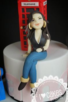 a cake with a woman sitting on top of it and a phone booth in the background