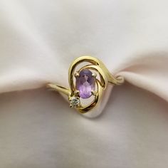 This ring has a  half carat oval amethyst and a small diamond in a 10K yellow gold Art Nouveau style setting! Amethyst is 6x4mm = .5 carats Diamond is 2mm = .03 carats Band is 2.74mm wide 2.30g Oval Amethyst Birthstone Ring In Yellow Gold, Oval Amethyst Diamond Ring In Yellow Gold, Oval Amethyst Ring With Diamond Accents For Anniversary, Anniversary Oval Amethyst Ring With Diamond Accents, Oval Amethyst Ring With Diamond Accents In Yellow Gold, Oval Amethyst Ring In Yellow Gold With Diamond Accents, Oval Diamond Amethyst Birthstone Ring, Swirl Diamond Ring, Tanzanite Earrings