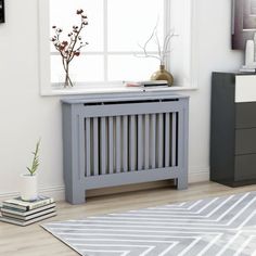 a grey radiator sitting in front of a window next to a white rug