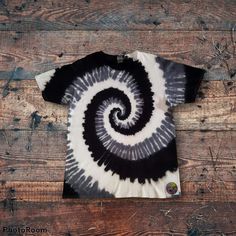 a black and white tie - dyed t - shirt sitting on top of a wooden floor