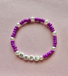 Stretch beaded bracelet purple with white pearl beads with words HOPE. Size Medium. 7 inches in length Purple Stretch Bracelet With 8mm Beads For Friendship, Handmade Purple Name Bracelet With Round Beads, Adjustable Purple Beaded Name Bracelet, Purple Beaded Bracelet With Letter Beads As Gift, Purple Beaded Name Bracelet With Round Beads, Purple Stretch Bracelet With Letter Beads, Purple Stretch Bracelet With Letter Beads For Gift, Purple Stretch Bracelet With Letter Beads As Gift, Adjustable Purple Name Bracelet With Letter Beads