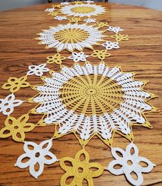 a wooden table topped with white and yellow doily on top of a wooden table