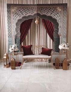 a white couch sitting in front of a window covered in red drapes and curtains