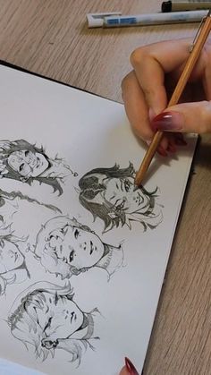 a person drawing faces on paper with pencils