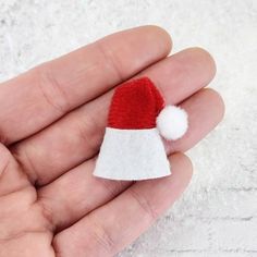 a small red and white santa hat on someone's hand