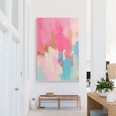 a painting hanging on the wall above a wooden bench in a room with white walls