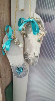 two white shoes with blue bows hanging from the side of a door, decorated with shells and seashells