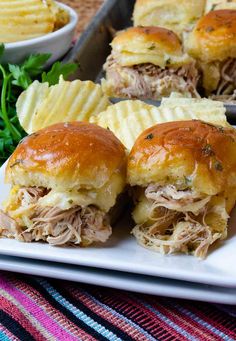 several sandwiches on a plate with potato chips and parsley in the backgroung