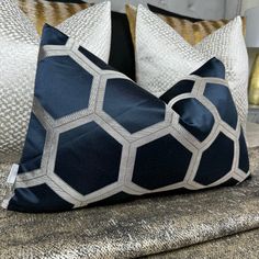 two blue and white pillows sitting on top of a couch