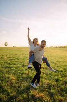 a man carrying a woman on his back in the middle of a field with grass