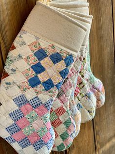 four quilted oven mitts hanging on a wooden wall