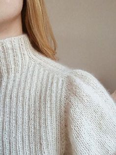 a woman with blonde hair wearing a white sweater