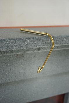 a pair of gold - plated metal hooks hang from the edge of a fireplace mantel