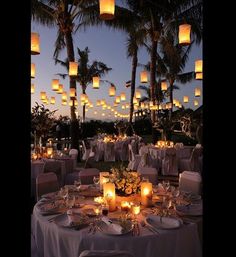 an image of a table set up for a wedding with candles and paper lanterns in the background