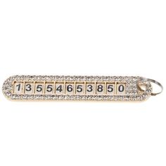 a gold key chain with numbers and diamonds on the keys, in front of a white background