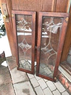 two glass doors sitting next to each other in front of a door with snow on the ground