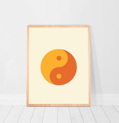 an orange and yellow yin - yang symbol on a white background in a wooden frame