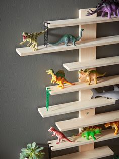 several toy dinosaurs on wooden shelves in a room