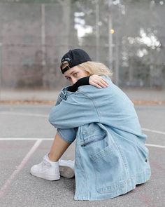 a woman sitting on top of a basketball court holding her head in her hands and covering her face