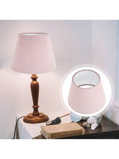 a pink lamp sitting on top of a table next to a book and a light