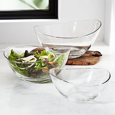 two clear bowls filled with salad on top of a white counter