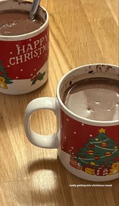 two mugs with hot chocolate in them sitting on a table next to each other