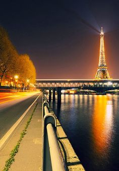 the eiffel tower is lit up at night with lights reflecting in the water