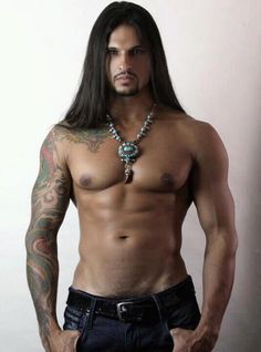 a shirtless man with long hair and tattoos on his chest is posing for the camera