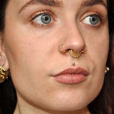 a close up of a woman with a nose ring and piercing on her nose looking at the camera