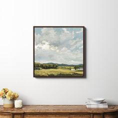 a painting hanging on the wall above a table with vases and flowers in front of it