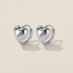 Heart goes padam padam in these hoops. Bae's chubby heart motif, set on a 8mm huggie, are the sweetest addition to your ear stack. Minimal, sophisticated and chic, these shapely hoops will have hearts skipping beats. Created for you in the finest 14 karat white gold, you'll want to wear these earrings always and never take them off, even when working out or in the shower. White Gold Huggie Cartilage Earrings, Anniversary Small Hoop Huggie Earrings With Heart Charm, Valentine's Day Small Hoop Huggie Earrings With Heart Charm, Trendy Huggie Heart Earrings For Valentine's Day, Single Huggie Earring For Valentine's Day, Everyday Heart Charm Huggie Earrings, Silver Heart Charm Huggie Earrings, Silver Huggie Earrings For Valentine's Day Elegant Style, Silver Huggie Earrings With Heart Charm For Anniversary