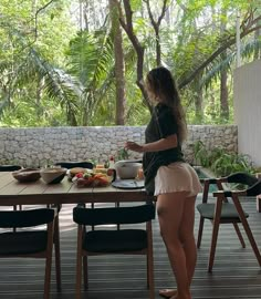 a woman standing in front of a table with food on it