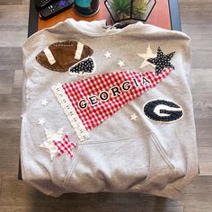 a sweatshirt with the word georgia printed on it sitting on a table next to a laptop