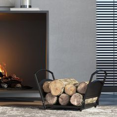 a fire place with logs in front of it and a chair next to the fire