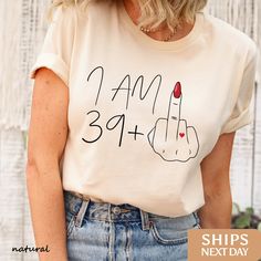 The Boho Boutiques Award-Winning I am 39+ Middle Finger t-shirt is perfect for any occasion. Our handcrafted hello 40 shirt, birthday shirt, 40th birthday shirt, birthday queen shirt, 40th birthday gift, 40th birthday party, 40th birthday, 40th birthday tshirt, birthday girl shirt, birthday squad shirt, birthday party shirt, 40 and fabulous, birthday group shirt designs are printed on the softest material with the highest quality eco-friendly ink available! We believe in only selling items using ink that is not only safe for the environment but also safe for your skin! ✧ Quick Sizing Tip ✧ All our t-shirts are unisex and fit great for both men and women. Women should order one (1) size down if they prefer a slimmer fit.  Our sweatshirts are unisex and fit great on both men and women. We re Cotton Tops For Anniversary In Summer, Cotton Tops For Summer Anniversary, Summer Cotton Tops For Anniversary, Summer Anniversary Graphic Print Tops, Funny 40th Birthday Gifts, Birthday Group Shirts, Funny 40th Birthday, 40th Birthday Shirt, Birthday Squad Shirts