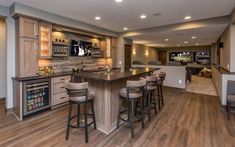 a large open concept kitchen and living room with wood flooring, built in bar area