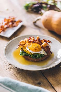 a plate with an egg and bacon sandwich on it next to some other food items