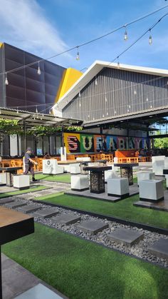 an outdoor dining area with tables and benches on the grass in front of a building