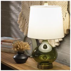 a table lamp sitting on top of a wooden table next to a vase and books