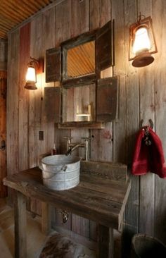 a rustic bathroom with wooden walls and wood flooring, an old wash basin sits on the counter